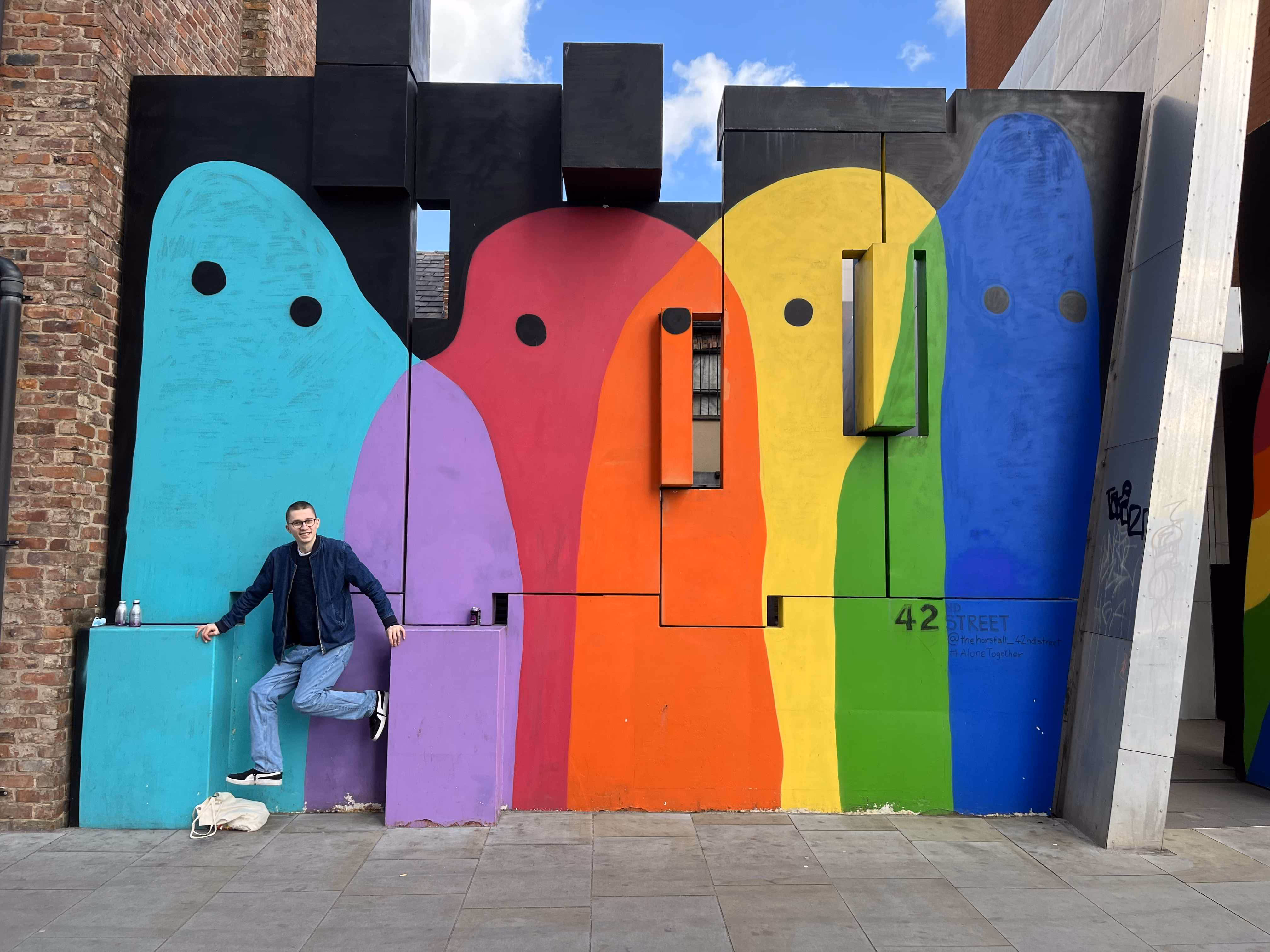 Charlie standing in front of a colour wall